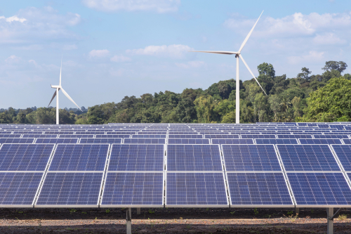 A field features solar panels and wind turbines, representing sustainable energy solutions in an open landscape.