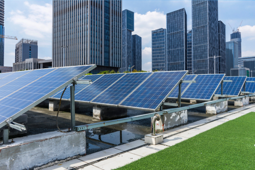 A roof equipped with solar panels, set against a backdrop of towering buildings in an urban environment.