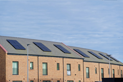 A series of residential homes with solar panels atop their roofs, emphasizing renewable energy use in the neighborhood.