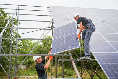 Two men working together on a solar panel installation, showcasing their commitment to sustainable energy solutions.