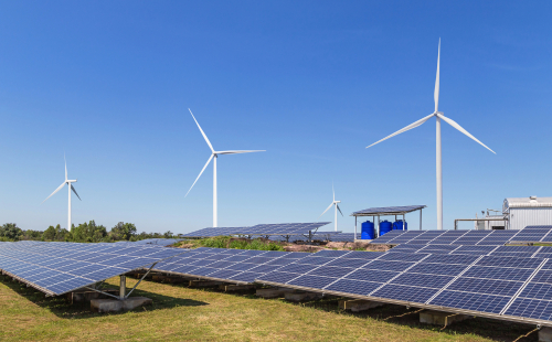 Solar panels and wind turbines are positioned in a field, highlighting the integration of renewable energy technologies.